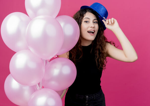 卷曲一位年轻漂亮的女士 一头卷发 戴着节日礼帽 手里拿着一堆气球 脸上洋溢着粉色的笑容粉色微笑美丽