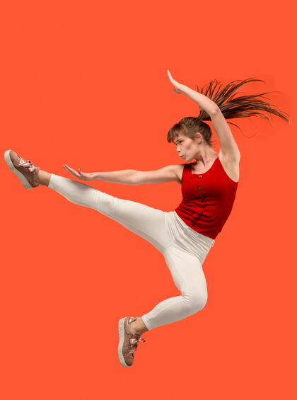 移动在移动的自由相当快乐的年轻女子跳跃和对橙色工作室的手势半空中拍摄模特成人人类