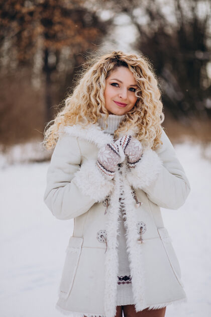 降雪一个卷发的年轻女人在冬天的公园里散步快乐公园温暖