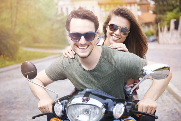 乐趣一对夫妇在城里骑摩托车春天夏天美丽