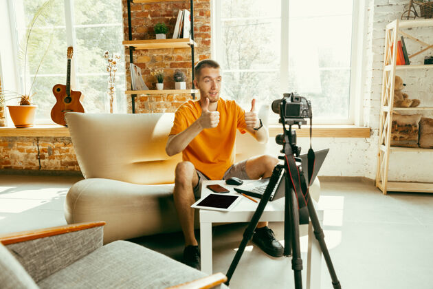 视频日志年轻的白人男性博主用专业相机录制视频评论家里的小玩意笔记本现实技术