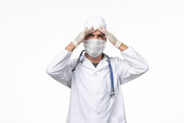 灯光正面图：男医生 穿着防毒服 戴着防毒面具 戴着蓝色听诊器 光壁上有冠状病毒病大流行病毒病毒大流行防护