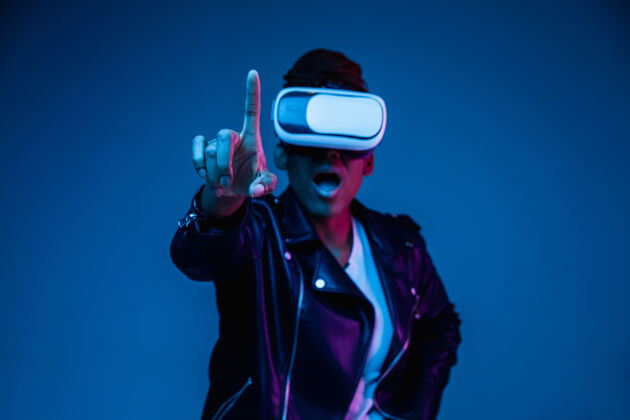 虚拟在蓝色背景的霓虹灯下 年轻的非洲裔美国妇女戴着vr眼镜玩耍的肖像霓虹灯人类虚拟现实