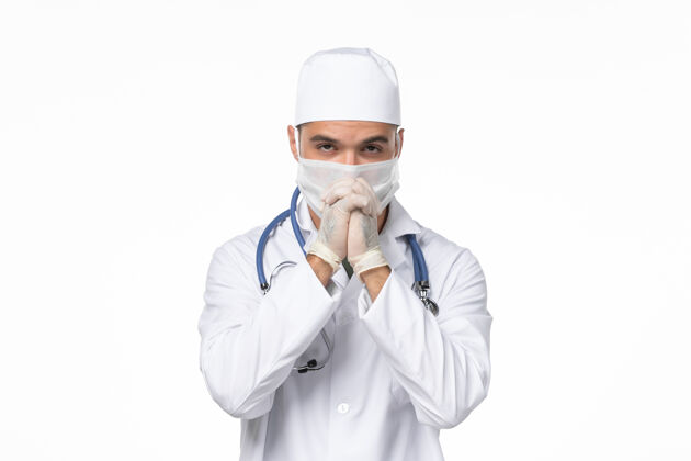 专业正面图：男医生穿着医疗服 戴着口罩 在白色墙壁上摆姿势 传染疾病医疗冠状病毒预防冠状病毒防护