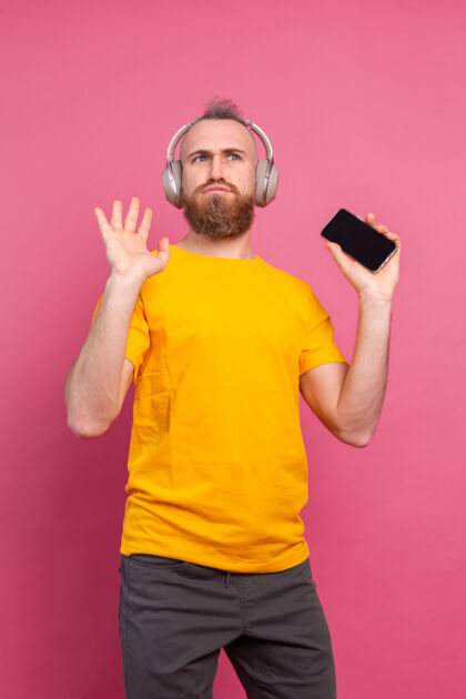 休闲帅哥带着手机和耳机在粉色背景上翩翩起舞收音机成人粉色