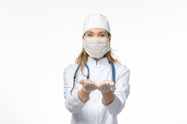职业正面图女医生穿着医疗服 带着无菌口罩因白墙上冠状病毒病健康到期正面制服