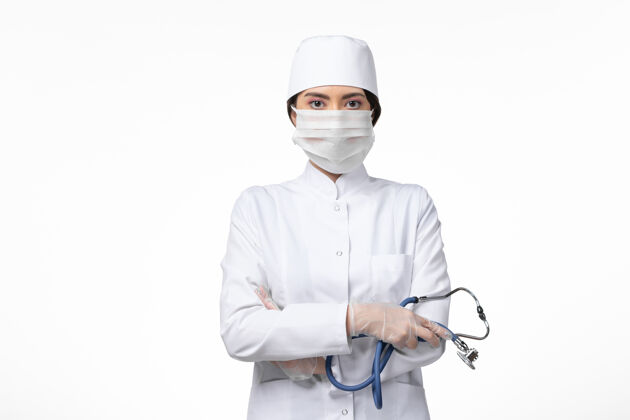 专业人员正面图：女医生穿着白色无菌医疗服 带着口罩 因为白色病床上的柯维德病毒病柯维德大流行病毒病灭菌前台面罩