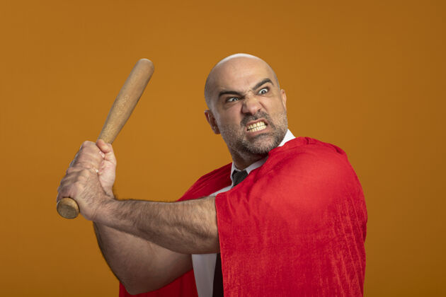 商人超级英雄商人在红斗篷挥舞棒球棒与愤怒的侵略性表情疯狂蝙蝠愤怒棒球