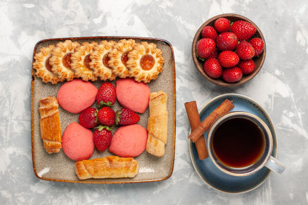食物白色桌面上有美味的百吉饼 蛋糕 新鲜草莓 茶和饼干蛋糕浆果甜点
