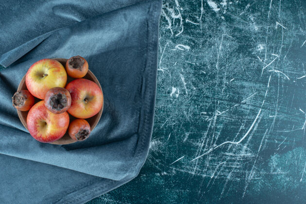 碗一小包枸杞果和苹果在碗里 在毛巾上 在蓝色的背景上高质量的照片美味有机水果