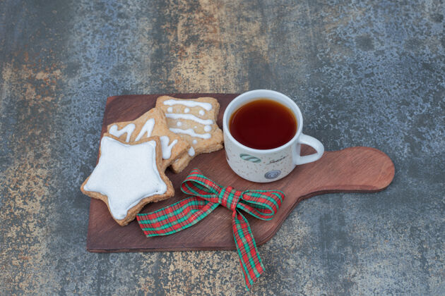 杯子星型姜饼饼干和一杯茶在木板上高品质的照片茶丝带节日