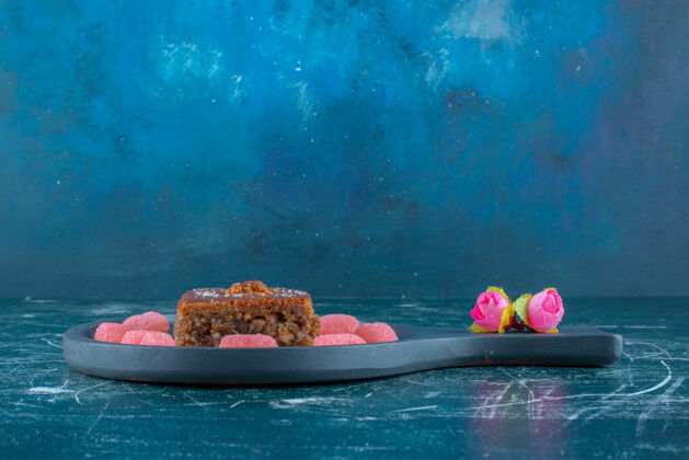 甜点在蓝色背景的小平底锅上 围绕着一片bakhlava的marmelades旁边的花冠高质量的照片口感美味糖