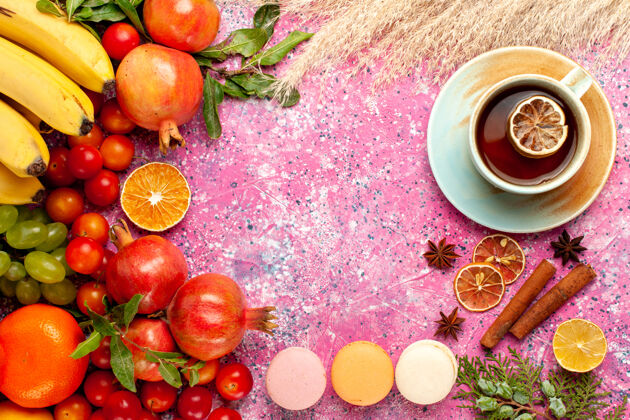 饮食顶视图新鲜水果成分与法国马卡龙和茶淡粉色表面蔬菜番茄洋葱