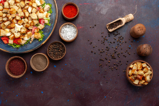 胡椒俯瞰凯撒色拉与不同的调味品对黑暗的桌子色拉食物餐午餐蔬菜封闭沙拉杯子