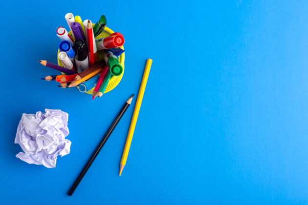 钢笔俯瞰蓝色书桌上不同颜色的铅笔和毛毡笔学校不同的书桌