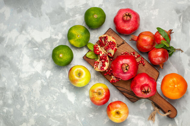食物在浅白的书桌上俯瞰新鲜的红石榴 橘子和苹果可食用的水果书桌石榴
