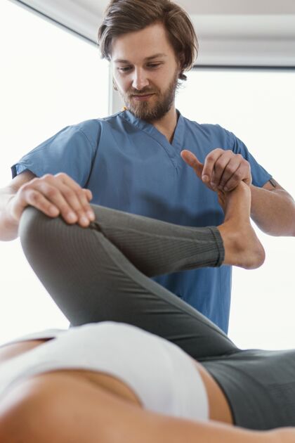 垂直骨科治疗师检查女性患者腿部运动的低角度骨病治疗师非侵入性