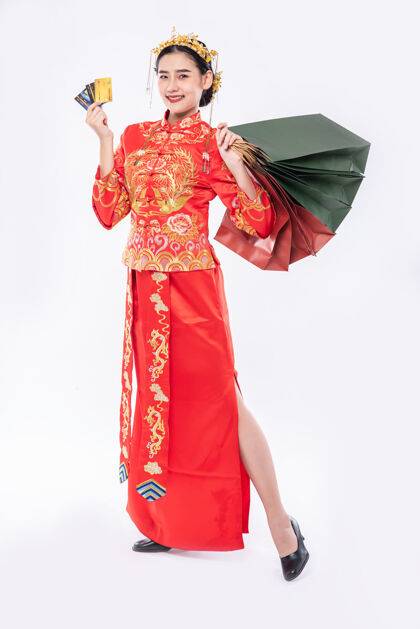 传统服装女人穿旗袍套装笑着用信用卡购物过年女孩纸袋中国文化