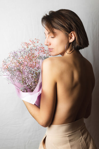 心情一位年轻女子的温柔写照 身穿白色抹布 赤裸上身 手持一束干枯多色的鲜花 微笑可爱 期待春天的到来植物新鲜模特