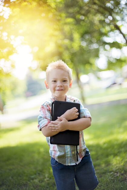 抱着一个孩子拿着圣经对着他的胸膛 同时看着相机的垂直镜头书童年小