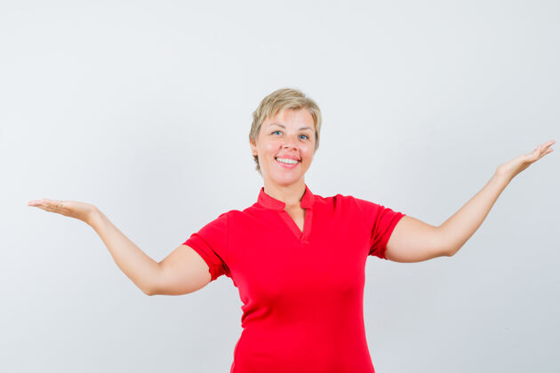 女性成熟的女人穿着红色t恤展示或比较一些东西 看起来很快乐东西女士活跃