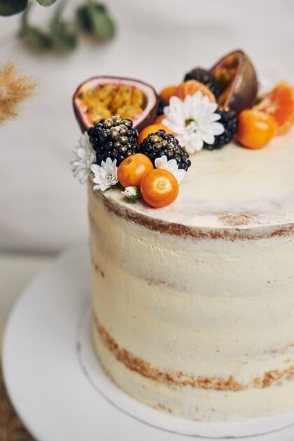 块白色蛋糕上有浆果和西番莲 旁边有一棵植物 后面是白色的美味焦糖热带