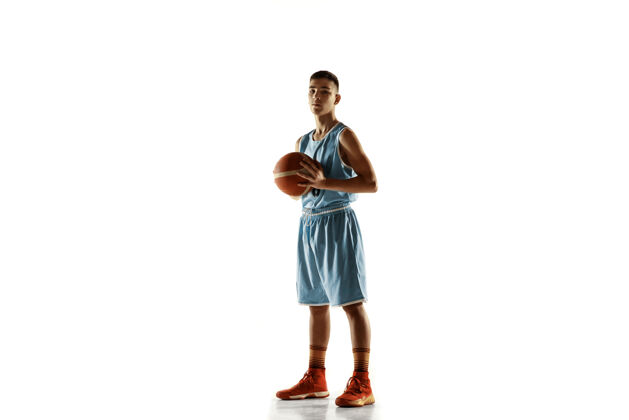 运动员在白色工作室背景上 年轻篮球运动员拿着一个球的全长肖像青少年自信地拿着球摆姿势运动的概念 运动 健康的生活方式 广告 动作 动作年轻球肖像