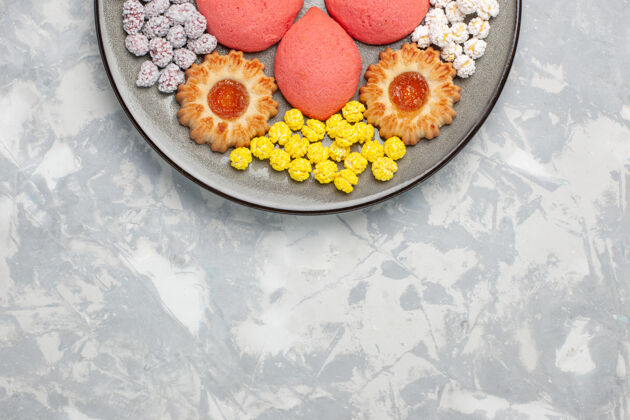 蛋糕顶视图白色桌子上的盘子里有糖果和饼干的粉红色蛋糕甜甜的烤蛋糕饼干茶派饼干饼干顶部生的