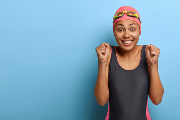 连体衣高兴的深色皮肤健康的游泳运动员握紧拳头 做出胜利的姿态泳装高兴乐观