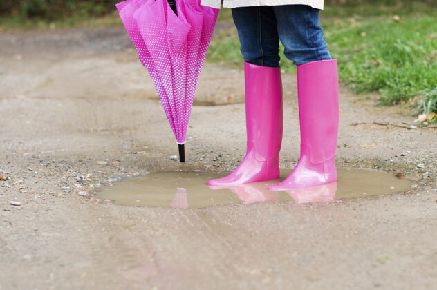 湿站在水坑里的年轻女人靴子雨低节