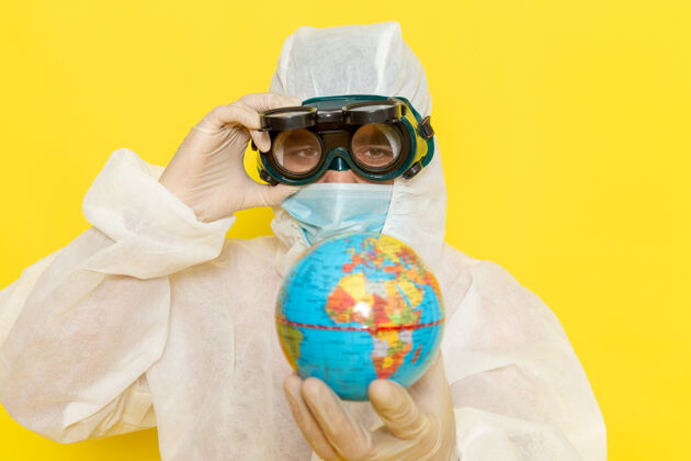 化学正面图：身着特殊套装的男科学工作者手持黄色表面上的小圆球圆男性科学