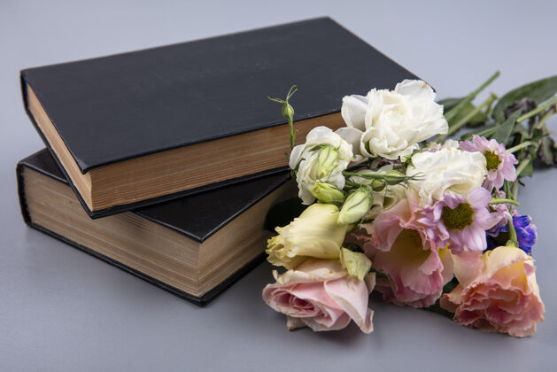 花灰色背景上的花朵和合上的书的侧视图壁板景灰