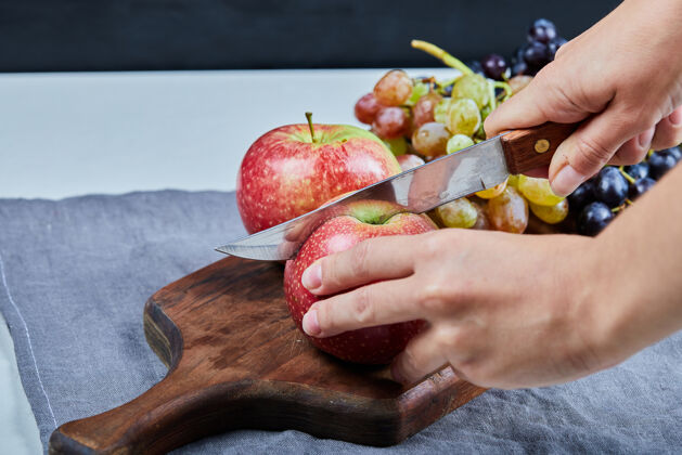 美味在果盘上切一个苹果 周围有葡萄异国情调素食产品