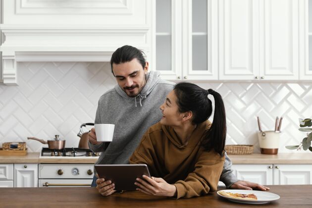 享受一对夫妇在厨房吃早餐 并使用平板电脑无忧无虑室内科技