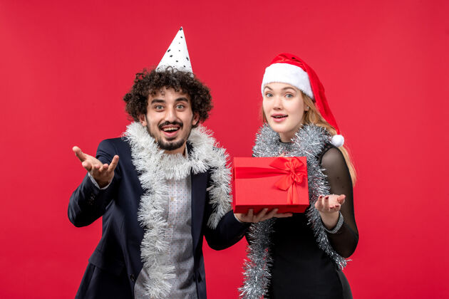 成人正面图年轻夫妇带着礼物在红地板上庆祝圣诞之爱礼物圣诞节年轻夫妇
