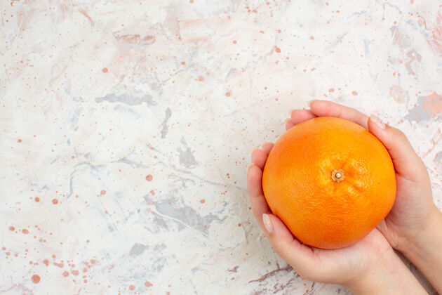 柑橘顶视图新鲜的橙色在女性手上明亮孤立的表面自由空间维生素顶级果汁