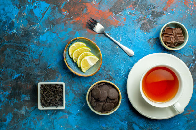 盘子俯视一杯茶巧克力凯蒙片叉在蓝红色的表面视图叉子杯子