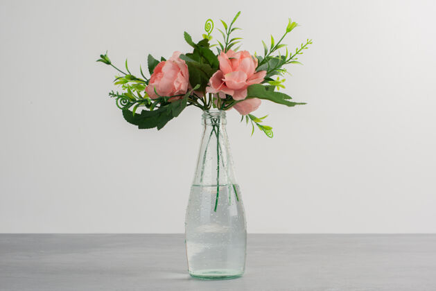 花瓣玻璃花瓶里的粉红色花朵和绿叶花自然叶子