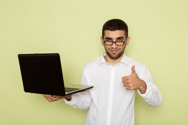 切肉刀身穿白衬衫的男办公室工作人员正拿着笔记本电脑站在浅绿色的墙上外套工作男性