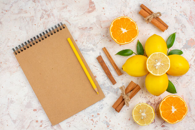 水果顶视图新鲜柠檬切橘子肉桂棒切橘子在女性笔记本黄色铅笔明亮孤立的表面顶部观点笔记本