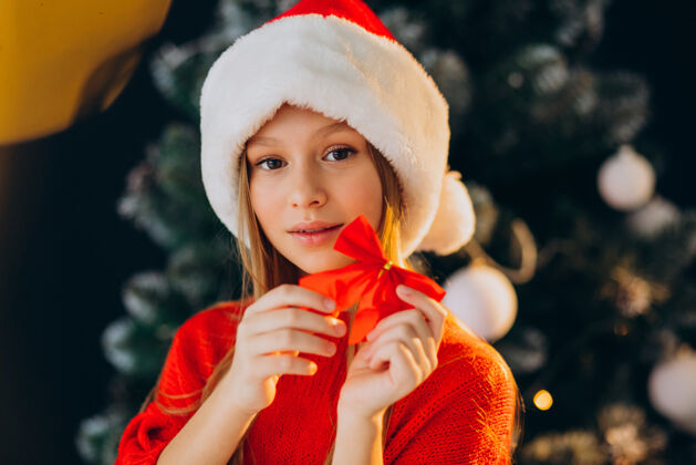 孩子可爱的少女戴着圣诞树旁的红色圣诞帽少年装饰欢呼