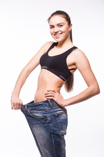 医疗年轻女子穿了一条旧牛仔裤来显示她的减肥效果腹部卡路里体重