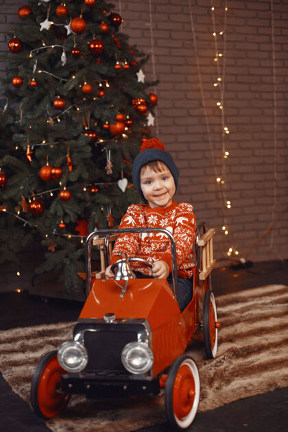 房间穿着红毛衣的可爱小男孩圣诞树旁的孩子幼儿欢呼毛衣