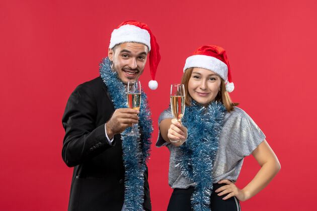 只是正面图年轻夫妇在红墙圣诞爱情派对上庆祝新年庆祝幸福帽子