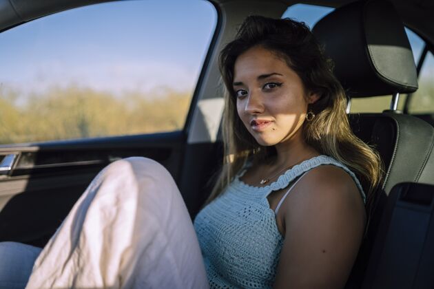 吸引力一个美丽的年轻白人女性在一个领域的汽车前排座位摆姿势的水平镜头皮革车身座椅