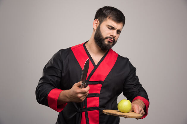 男人严肃的男人拿着苹果和刀拿着木板模型脸男人