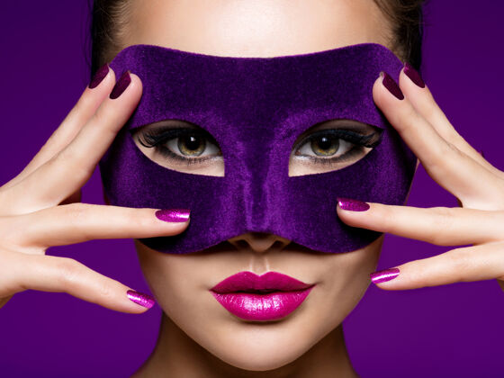 化妆一个漂亮女人的肖像 紫色的指甲 脸上戴着紫色的戏剧面具穿着时尚面具