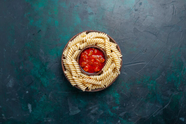 技术在深蓝色的桌子上可以俯瞰意大利面食和番茄酱菜甜点背景