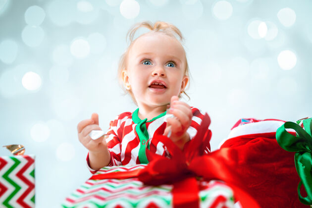 小可爱的女婴1岁附近的圣诞帽坐在地板上与圣诞球年轻成长玩