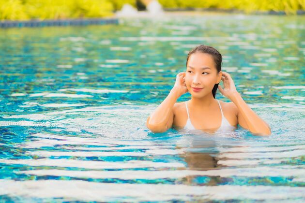 人肖像美丽的亚洲年轻女子放松微笑休闲围绕室外游泳池近海阳光休息游泳